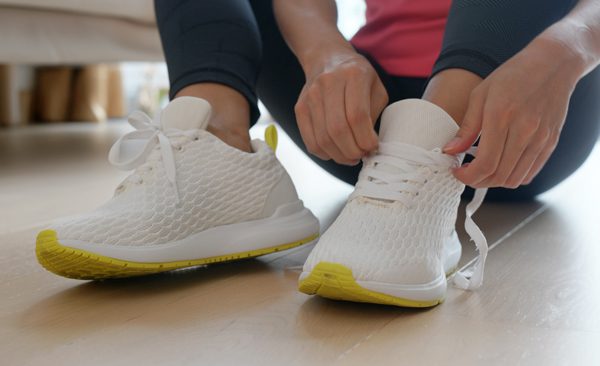 closeup of woman putting on running shoes - exercise